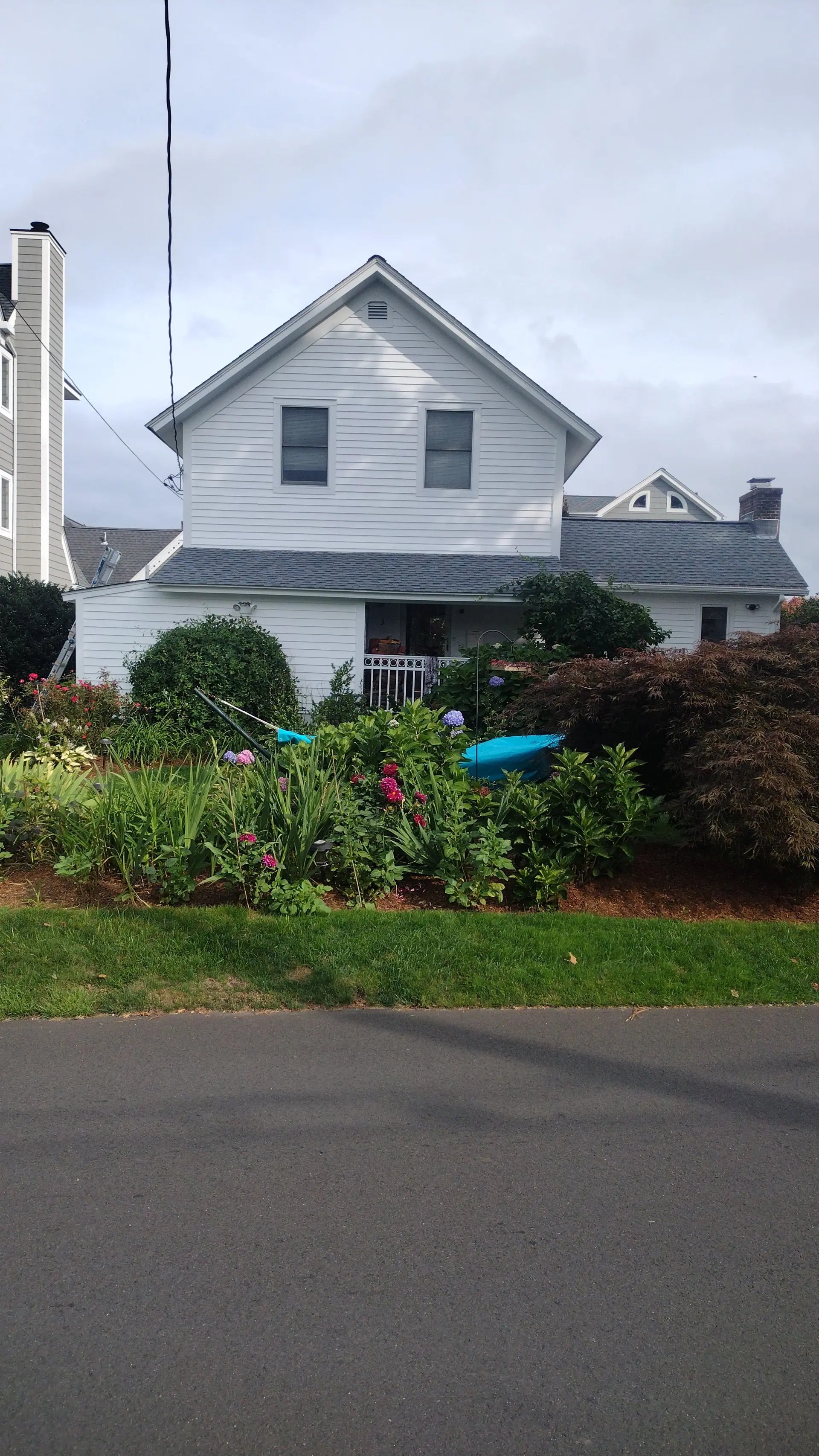 White farmhouse with a fresh exterior repaint, seen from the street