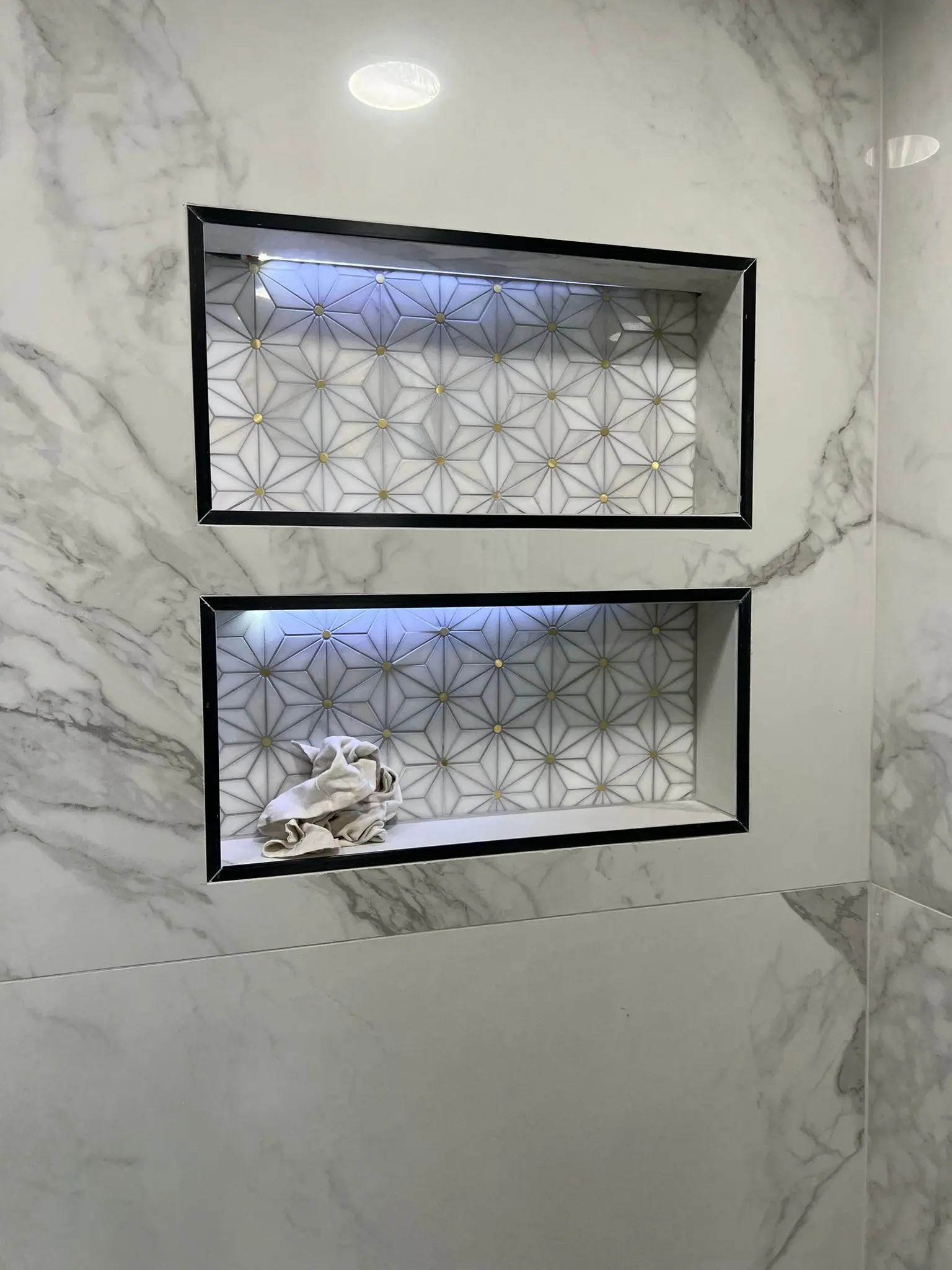 Two lit shower niches with patterned tile backs