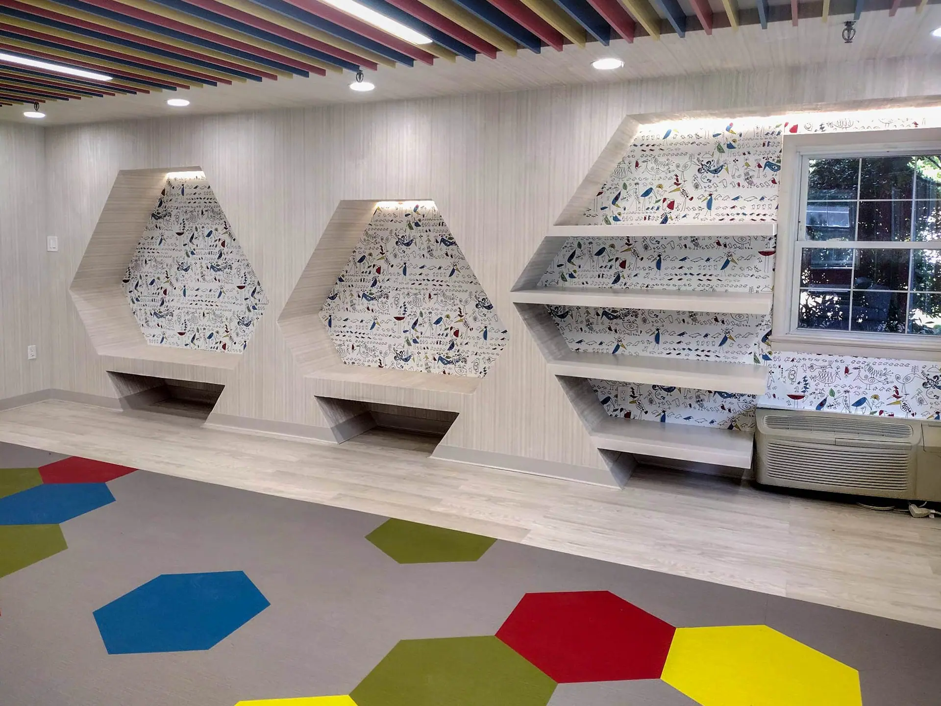 Playroom with built-in hexagonal reading niches and a colorful floor
