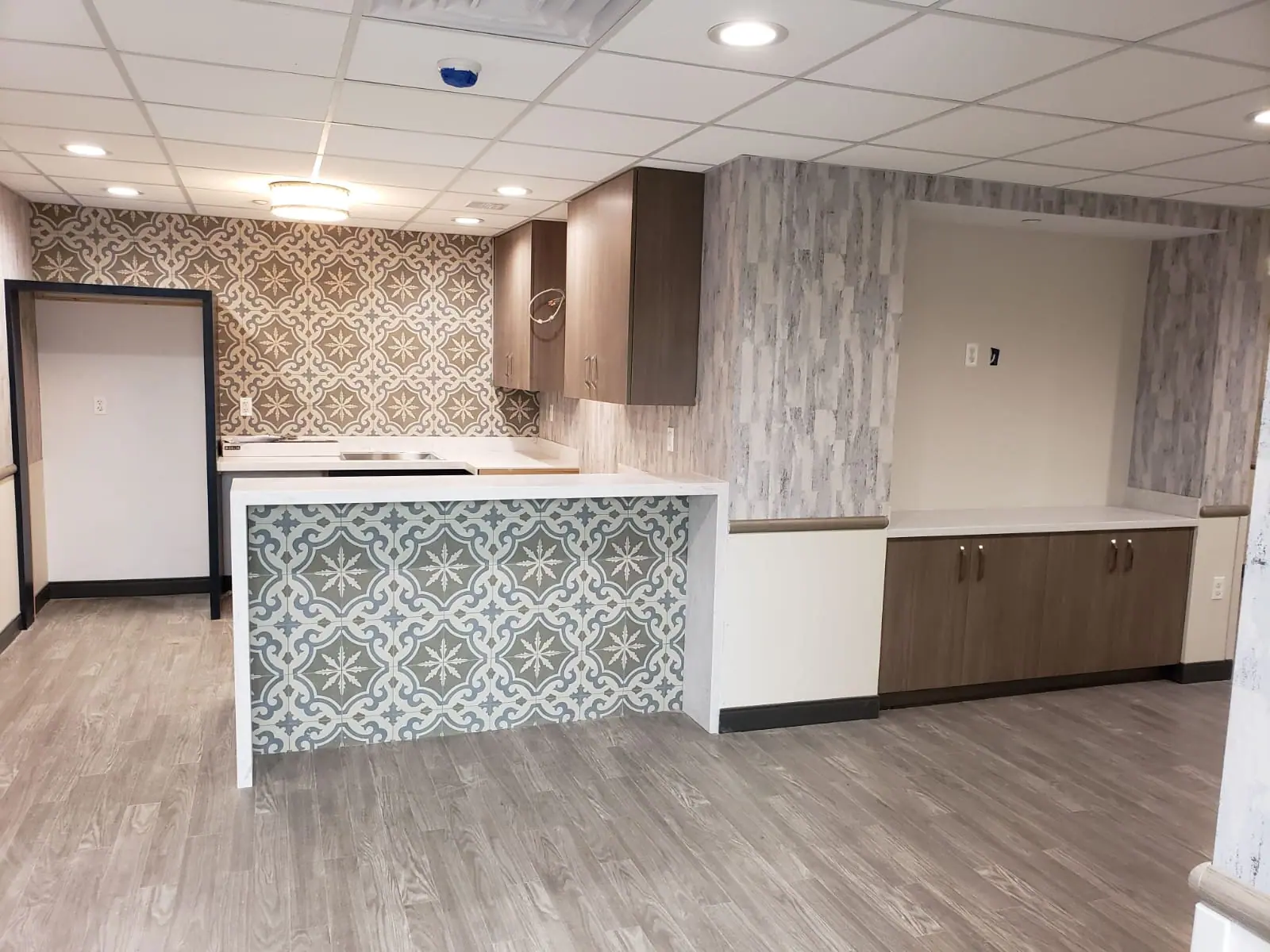 Kitchenette with a patterned tile island and wood-grain cabinets